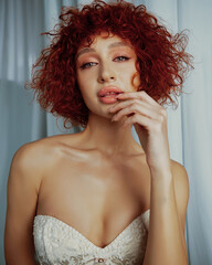 Portraits of an attractive girl with curly hair and a slim figure in the studio