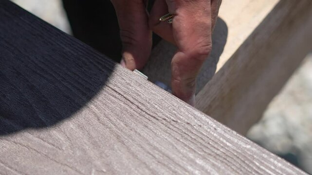Composite Deck Board Installation hand installing new decking outdoors