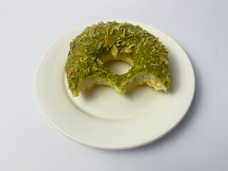 Delicious matcha donut with a bite missing, isolated on a white background