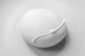 Buffalo mozzarella from Campania photographed on a neutral background. The fresh and artisanal texture. Realistic and minimalist image, with a high gastronomic and visual value.