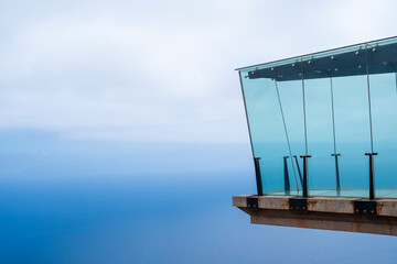 A glass structure with a view of the ocean. The glass is clear and the structure is tall
