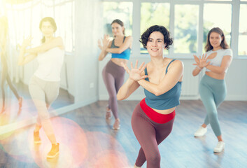 Fototapeta premium Positive incendiary female teacher conducts modern dance lessons for group of girls. Active hobby, movement, learning modern dynamic dances