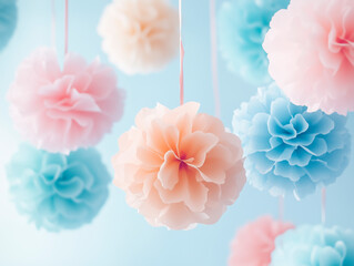 Soft pastel tissue pom-poms hang against a light blue background, creating a dreamy decoration scene.