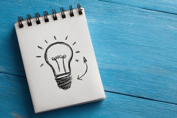 Creative sketch of a lightbulb and arrow on a notepad symbolizes innovative ideas and business development strategies for aspiring entrepreneurs