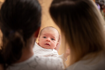 Two parents holding their newborn baby, admiring him with deep love and care, creating a heartwarming moment filled with joy, tenderness, and the beauty of family connection