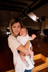 Portrait of a happy young mother holding her newborn baby in a cozy home environment, creating a heartwarming scene of maternal love and bonding