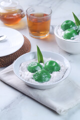 Kue Bugis Mandi or Putri Mandi. Is Indonesian traditional dessert made from steamed glutinous rice filled with palm sugar paste, served with coconut milk
