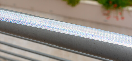 Iridescent holographic bird repellent tape reflecting sunlight on a railing