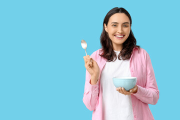 Young woman with tasty soup on blue background