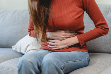 asian young woman intolerance hand in stomach ache, suffer from food poisoning, abdominal pain and colon problem