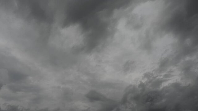 Timelapse looking up at a sky filled with gray colored rain clouds as they move across the frame