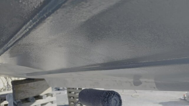 Applying epoxy primer to boat hull with roller at the boatyard