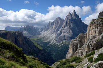 Naklejka premium Mountain valley view with sharp peaks grassy slopes and cloudy skies on a sunny day