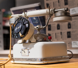  vintage rotary dial telephone with a cream-colored body, black dial, and metal earpiece. The...