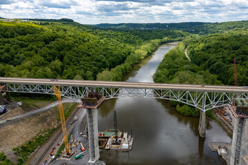 Fototapeta premium Crane lifting materials on bridge over river.