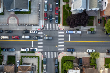 Cars moving through a busy street intersection with pedestrians using the crosswalk.