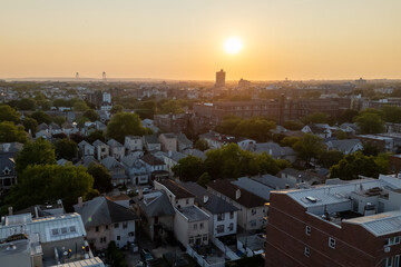 City buildings and trees silhouetted against a vibrant sunset sky.