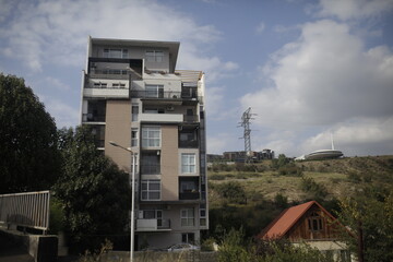 Modern apartment building in Tbilisi, Georgia, with a unique architectural design.  A distant view of the Tbilisi Concert Hall adds to the city landscape.