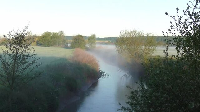 Stimmungsvoller Fluss am Morgen mit sanften Nebelschwaden &ndash; faszinierende Ruhe und zauberhafte Lichtstimmung in einer nat&uuml;rlichen Flusslandschaft bei Sonnenaufgang, Landschaft, Natur, Gew&auml;sser
