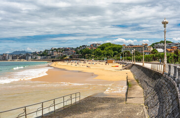 Obraz premium Ondarreta beach with people enjoying the first sunny days of summer, San Sebastian, Basque Country