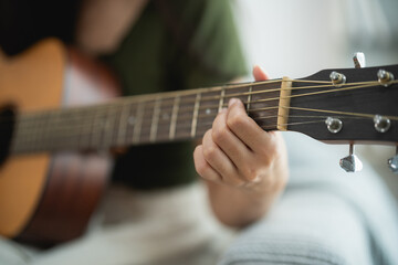 Person Playing Acoustic Guitar in a Relaxed Indoor Setting
