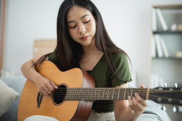 Young Woman Playing Acoustic Guitar at Home in Cozy Living Room