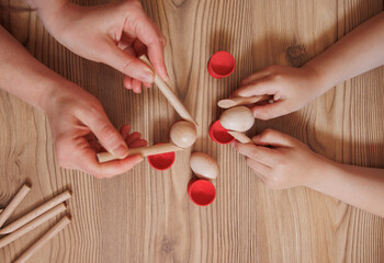 
Early child development and parent-child bonding activities indoors.top view.child and mother hands playing with wooden sticks on floor.