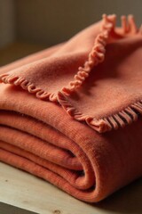 Close-up of a luxuriously soft, folded cashmere throw blanket, rich texture and deep color, displayed on a minimalist wooden surface , warm, texture, cream
