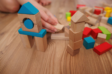 child 's hand playing building wooden blocks