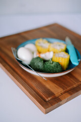 Plate of healthy vegetables and eggs on wooden board closeup