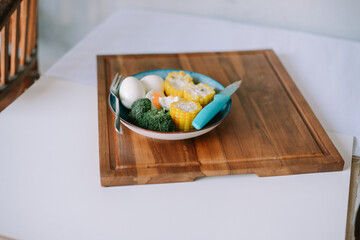 Healthy food presentation with boiled eggs and corn on wooden plate