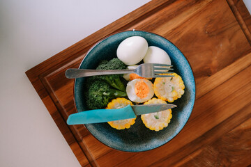 Nutritious plate with eggs, broccoli, and corn on a wooden board