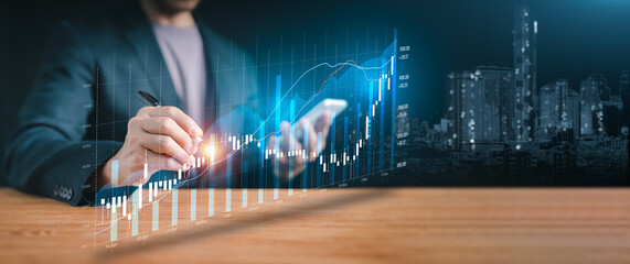 Financial technology and success: Hand holding a pen over a holographic display of increasing statistics, depicting innovation in finance and future market potential.
