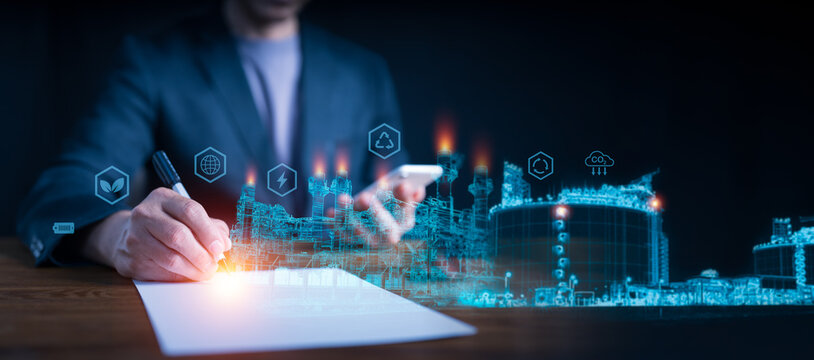 Sustainable industrial development: Businessman signing a document over a holographic projection of an eco-friendly factory with green energy icons.