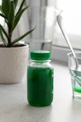 A bottle of aloe healing gel and a glass of gel diluted in water on the background of an aloe flower. The concept of using natural plants in the treatment of stomach diseases. Vertical photo