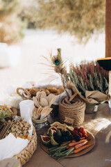 Outdoor picnic table with fresh fruits, vegetables, snacks, and wooden cutlery in warm natural light. Rustic and eco-friendly food setup.