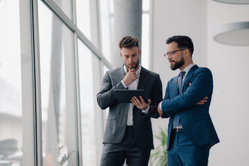 Businessmen using digital tablet, discussing business strategy in office