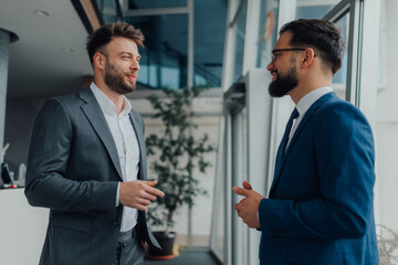 Two businessmen talking and discussing during break in office hallway