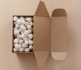 Top view of biodegradable with corn-based packing peanuts inside a kraft shipping box. Perfect visual for logistics, packaging industry, and online shopping themes