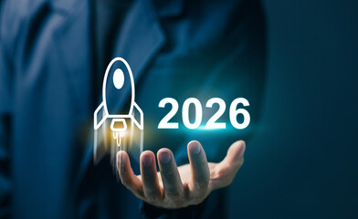 A businessman holding a glowing rocket icon and the number 2026, symbolizing future growth, startup success, innovation, and new business opportunities.