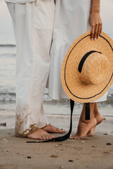 Romantic barefoot moment on the beach. Couple in white clothes stands close in soft evening light. Warm, natural and intimate coastal scene.