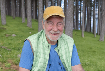 Portrait of relaxed Senior bearded man in outdoor excursion in the forest. Elderly male enjoys...