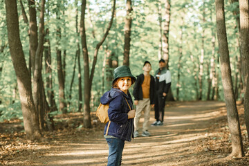 Fototapeta premium Cute little kid girl go hiking trip with backpacks at mountain forest with family. Explorer and adventure concept.