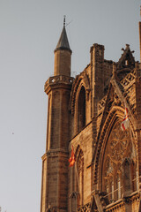 Golden hour view of a Gothic-style cathedral with a minaret, showcasing a unique blend of Christian and Islamic architecture. Captured with warm, soft light.