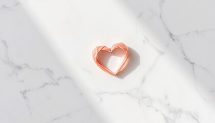 Heart-shaped origami on a marble surface with soft sunlight
