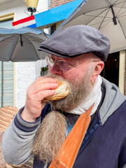 bärtiger Mann genießt ein Fischbrötchen mit Hering