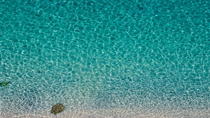 Aerial view of clear turquoise water gently lapping the white sandy shore in Tropea, Calabria,...