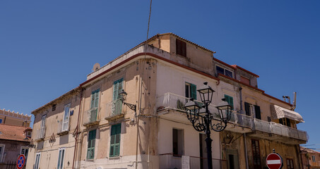Traditional architecture featuring balconies, green shutters, and a street lamp in Tropea, Calabria, Southern Italy, under a clear blue sky