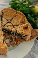 Outdoor summer picnic scene with a homemade lemon poppy seed pie, fresh lemons, mint, and lemonade on a rustic wooden table in a garden setting. Cozy and vibrant natural atmosphere.