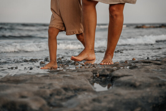 Tender beach moments between parent and child — collecting seashells, walking barefoot on sand, and enjoying a calm seaside sunset.